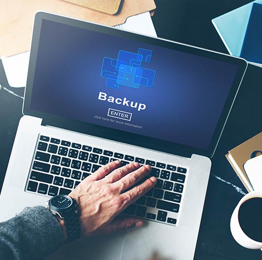 A person using a laptop with a "Backup" prompt on the screen.